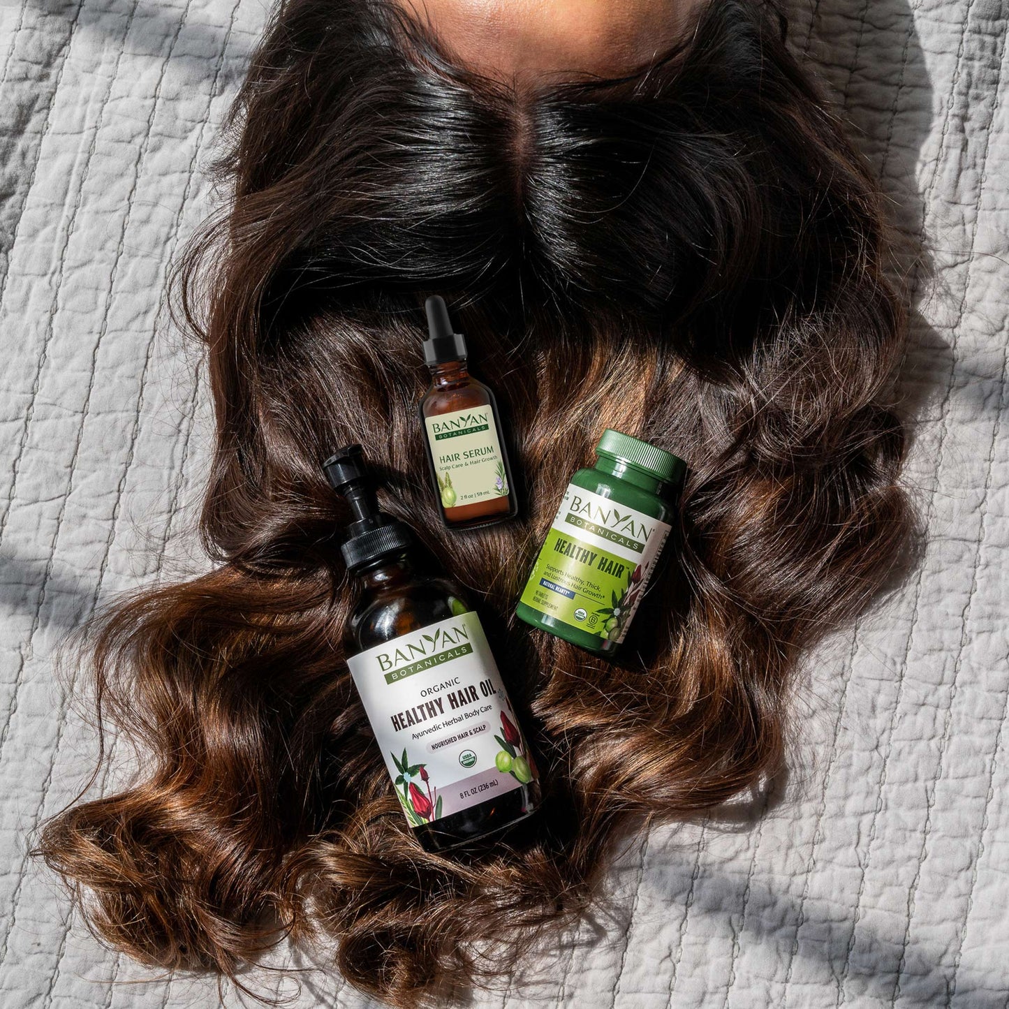 Woman holding healthy hair tablets and healthy hair oil near hair