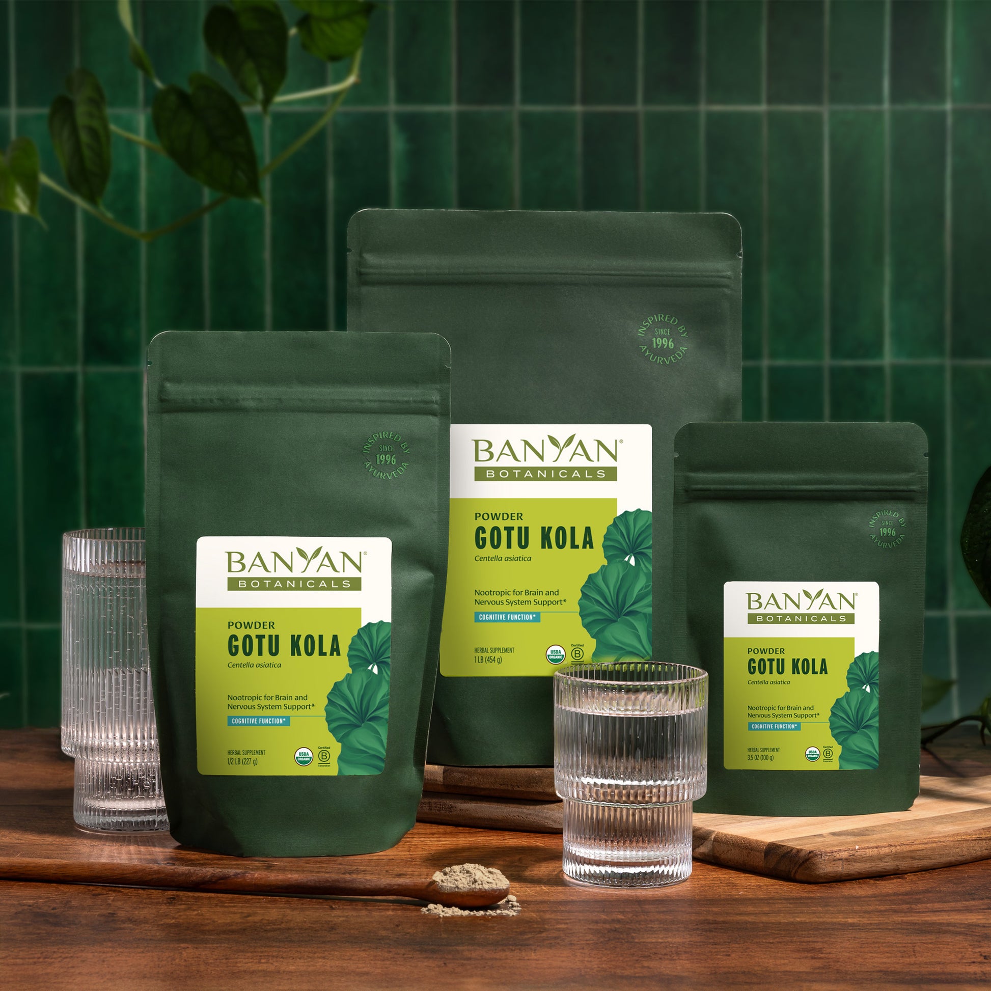 All three sizes of Gotu Kola pouches on a wooden surface with a green tiled wall background.